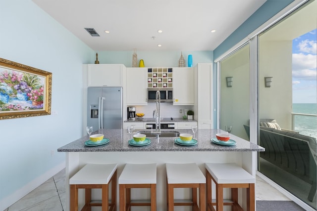 kitchen featuring white cabinets, stainless steel appliances, a breakfast bar, and visible vents
