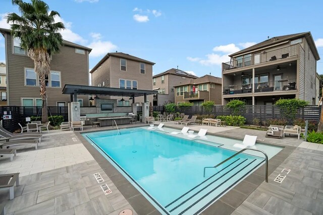 community pool with a ceiling fan, a patio area, fence, and a residential view