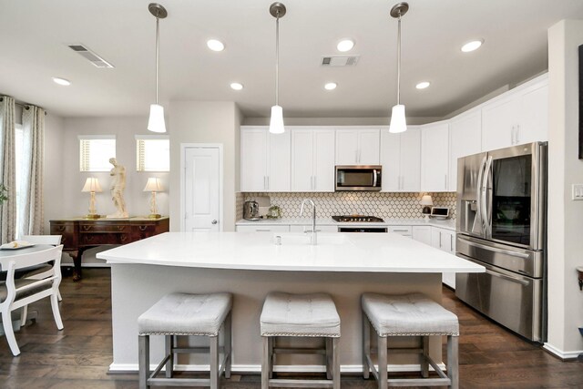 kitchen with dark wood-style flooring, appliances with stainless steel finishes, visible vents, and tasteful backsplash
