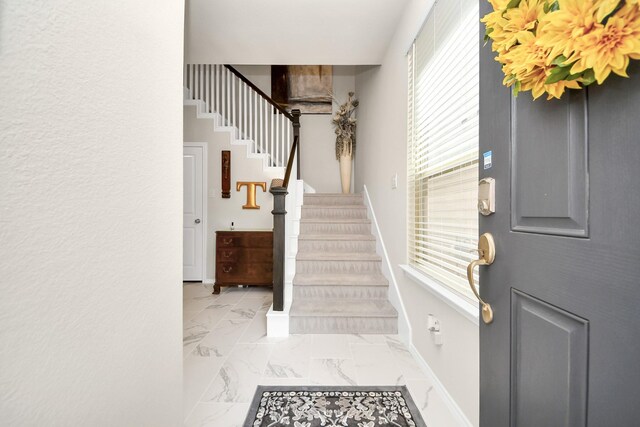 interior space featuring baseboards, stairway, a healthy amount of sunlight, and marble finish floor