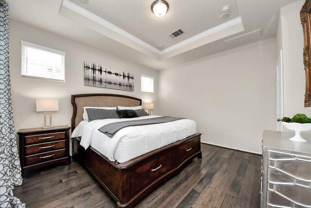 bedroom with visible vents, crown molding, a raised ceiling, and dark wood-type flooring