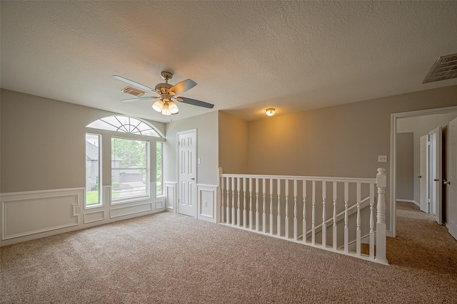 215 Wood Circle Ln, Houston, TX 77015 - carpeted empty room featuring ceiling fan, a textured ceiling, wainscoting, and a decorative wall