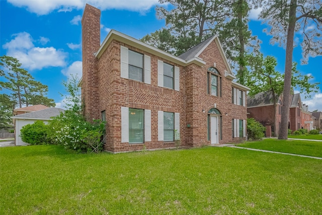 colonial inspired home featuring a chimney, brick siding, and a front yard