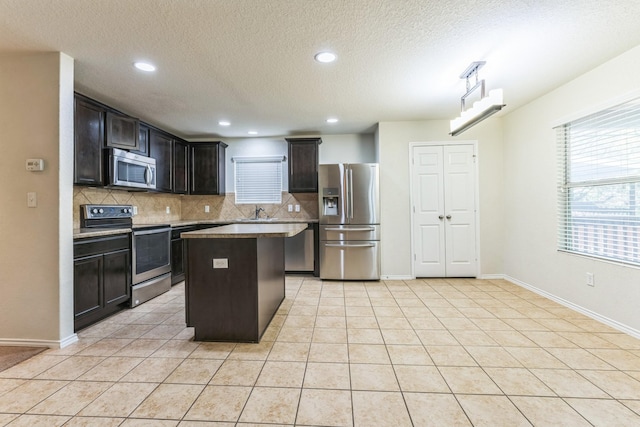 315 Prato Brezza, San Antonio, TX 78253 - kitchen featuring appliances with stainless steel finishes, decorative backsplash, a center island, a textured ceiling, and light tile patterned flooring
