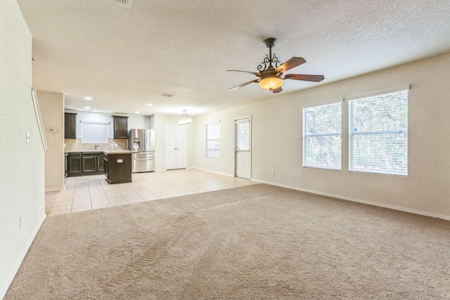 315 Prato Brezza, San Antonio, TX 78253 - unfurnished living room featuring light colored carpet, baseboards, a ceiling fan, light tile patterned flooring, and a textured ceiling