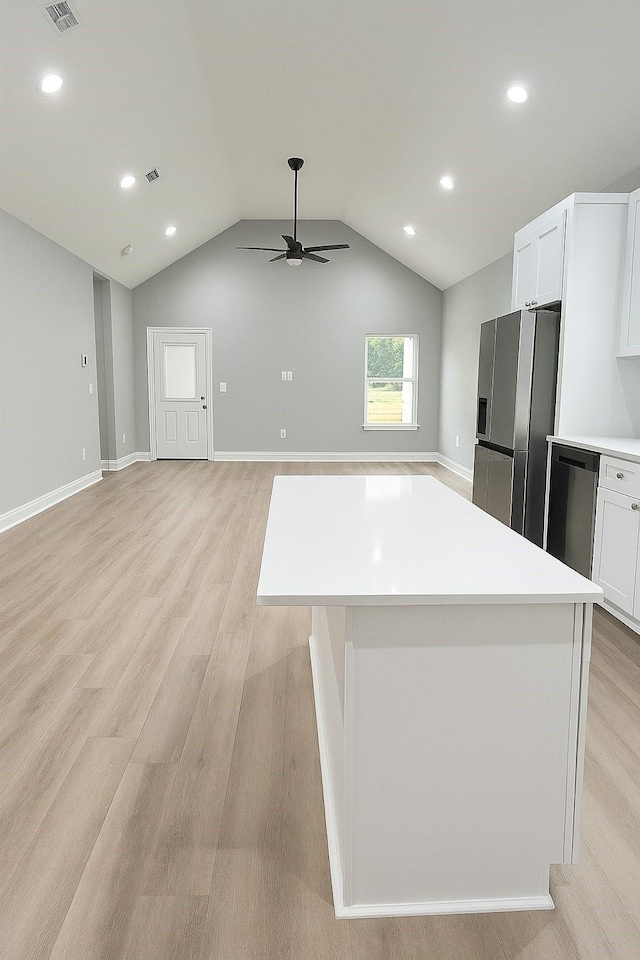 25759 Hickory Ln, Splendora, TX 77372 - kitchen with stainless steel fridge, a ceiling fan, light wood finished floors, white cabinets, and vaulted ceiling