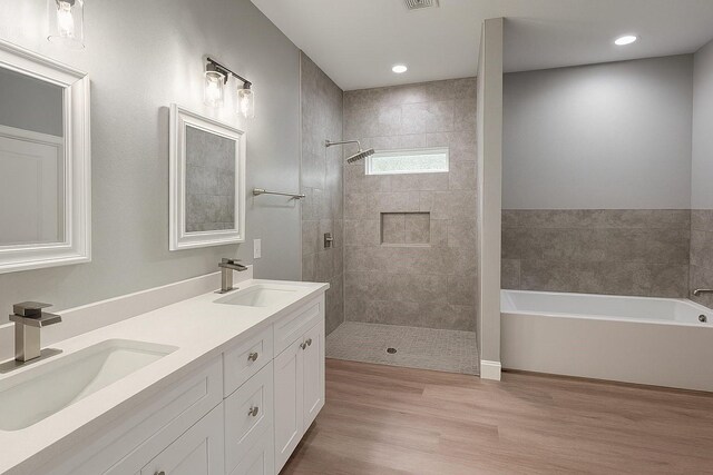 25759 Hickory Ln, Splendora, TX 77372 - bathroom featuring a garden tub, double vanity, a tile shower, wood finished floors, and recessed lighting
