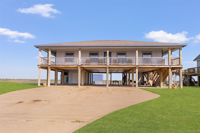 back of property with a shingled roof, a carport, a yard, stairs, and driveway