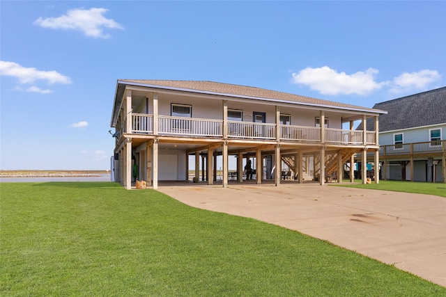 rear view of house featuring a carport, a lawn, driveway, a garage, and a shingled roof