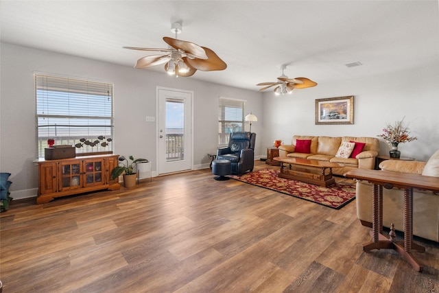living area with visible vents, baseboards, a ceiling fan, and wood finished floors