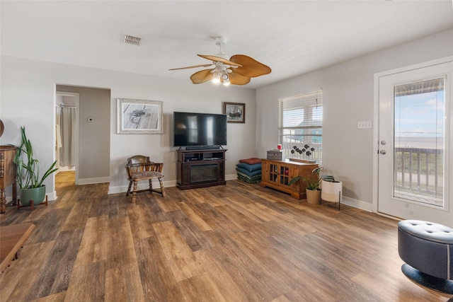 living room with visible vents, baseboards, a ceiling fan, and wood finished floors