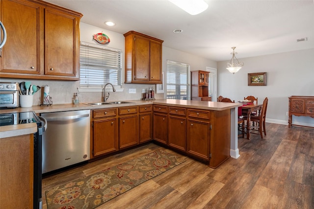 kitchen with dishwasher, a sink, a peninsula, brown cabinets, and dark wood-type flooring