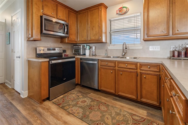 kitchen with dark wood finished floors, light countertops, a sink, and appliances with stainless steel finishes