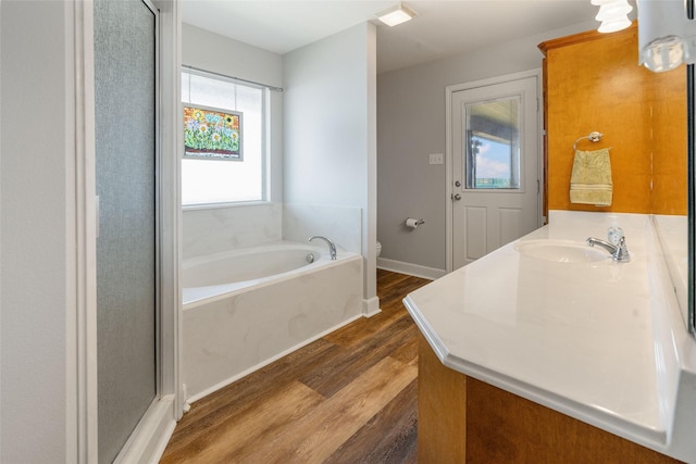 full bathroom featuring a bath, vanity, toilet, wood finished floors, and baseboards