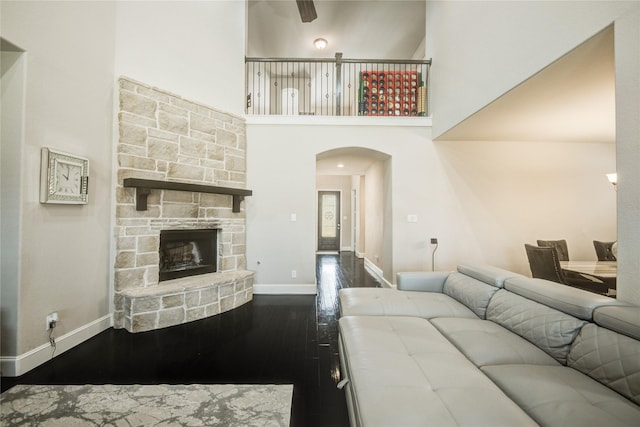 19810 Quarry Stone Ln, Richmond, TX 77407 - living room featuring a fireplace, dark wood-type flooring, arched walkways, a high ceiling, and baseboards