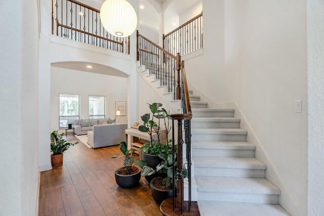 stairway with wood-type flooring, a high ceiling, and baseboards