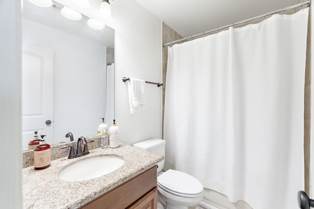 full bathroom with vanity, a textured wall, curtained shower, and toilet