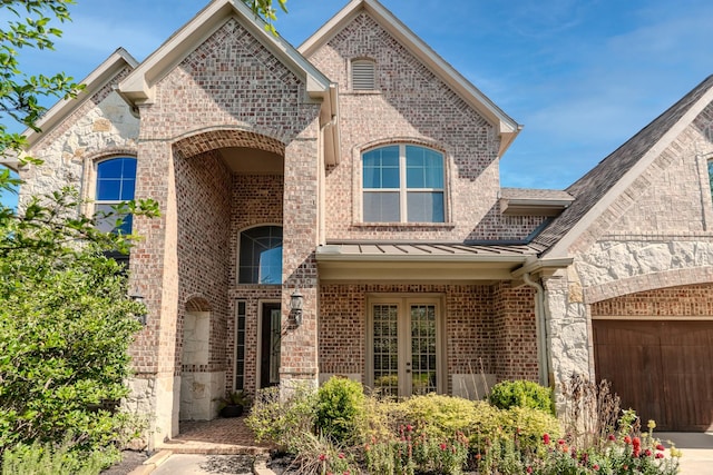 entrance to property featuring a standing seam roof, a shingled roof, a garage, and brick siding