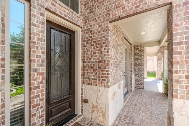 property entrance featuring a porch and brick siding