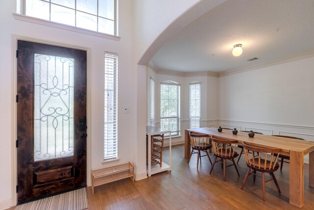 foyer entrance with visible vents, arched walkways, wood finished floors, and a wealth of natural light