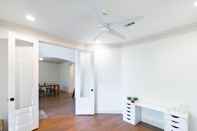 unfurnished room with crown molding, arched walkways, a ceiling fan, and dark wood-style flooring