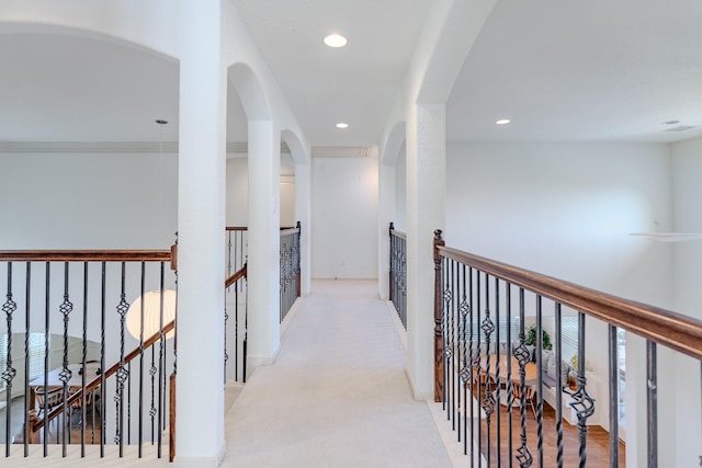 corridor featuring recessed lighting, carpet flooring, arched walkways, and an upstairs landing