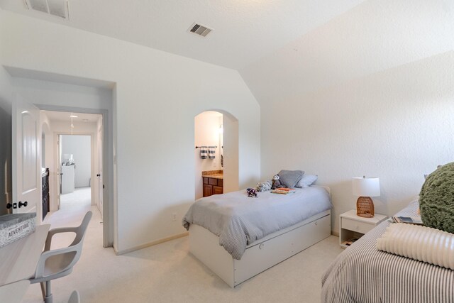 bedroom with light colored carpet, arched walkways, and visible vents
