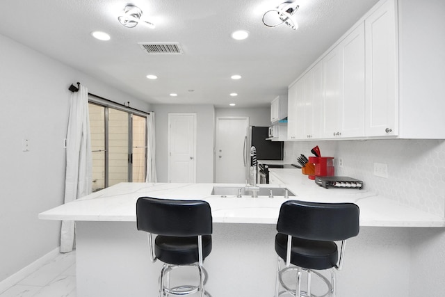 6430 Grandvale Dr, Houston, TX 77072 - kitchen with light stone counters, recessed lighting, a peninsula, white cabinetry, and visible vents