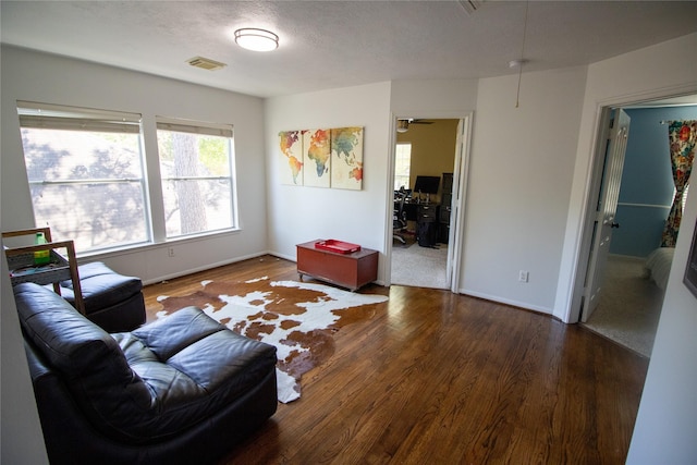 living area with wood finished floors, baseboards, and a textured ceiling