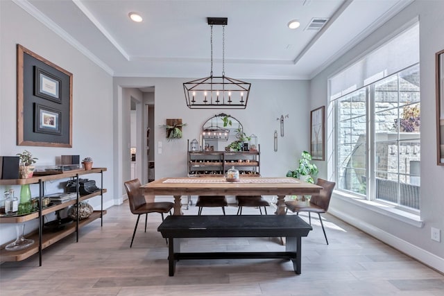 dining area featuring a tray ceiling, light wood-style floors, an inviting chandelier, and baseboards