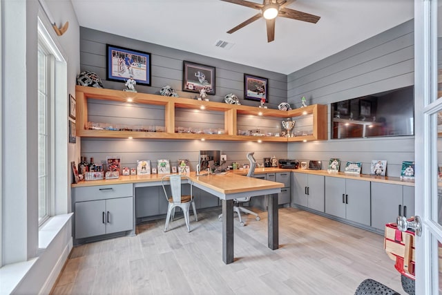 home office featuring light wood finished floors, visible vents, built in desk, and ceiling fan