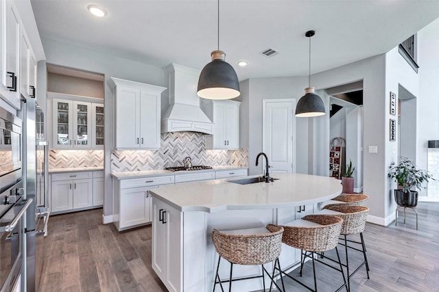 kitchen with tasteful backsplash, light wood-type flooring, premium range hood, visible vents, and stainless steel gas stovetop