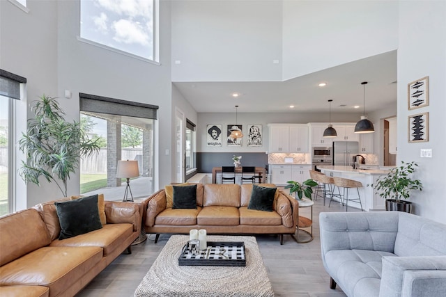 living area featuring recessed lighting, light wood-type flooring, and a high ceiling