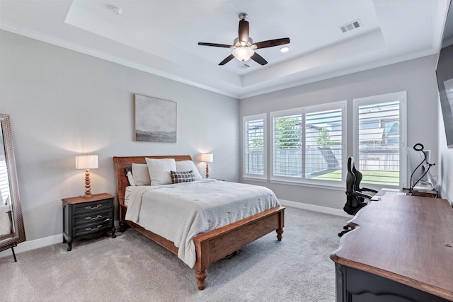 bedroom with baseboards, light carpet, visible vents, a tray ceiling, and ceiling fan