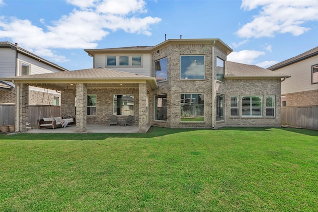 rear view of property featuring a patio, a yard, fence, and brick siding