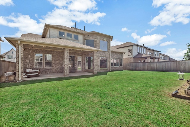 rear view of property with a patio, a yard, a fenced backyard, and a shingled roof