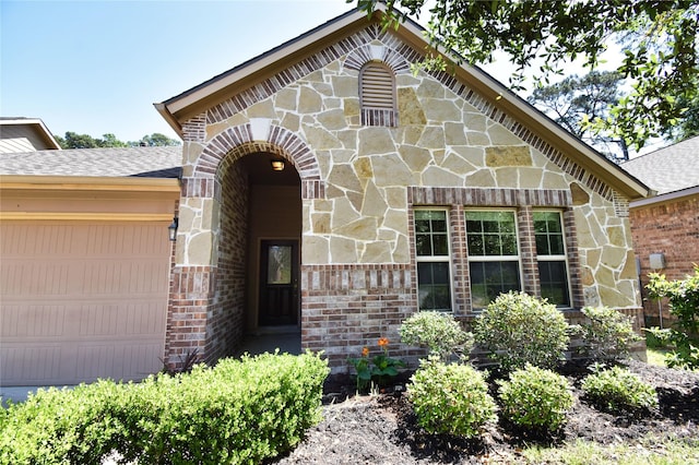 24034 Schults Meadow Ln, Spring, TX 77389 - tudor house featuring an attached garage, stone siding, brick siding, and roof with shingles