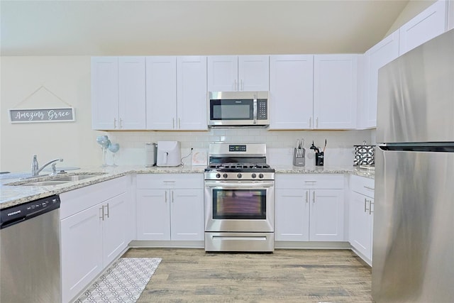 kitchen with light wood-style flooring, appliances with stainless steel finishes, a sink, and white cabinets