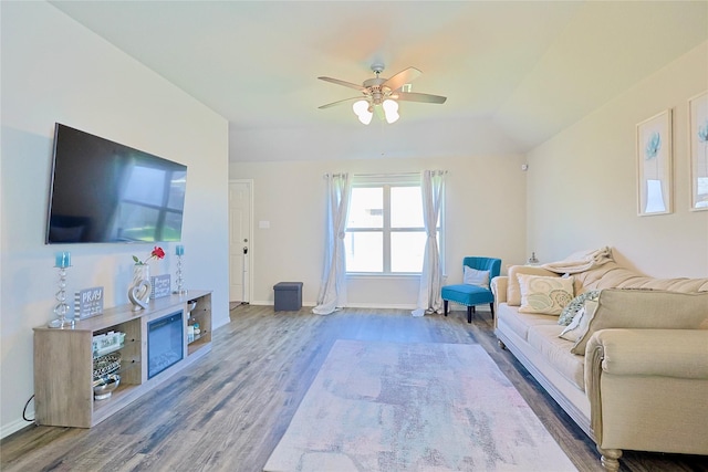 living room with ceiling fan, vaulted ceiling, wood finished floors, and baseboards