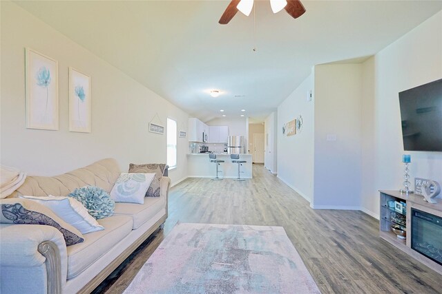 living area featuring light wood-style floors, baseboards, and a ceiling fan