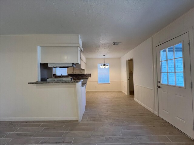602 Rosewood Dr, Shenandoah, TX 77381 - kitchen with a textured ceiling, white cabinetry, a chandelier, pendant lighting, and baseboards