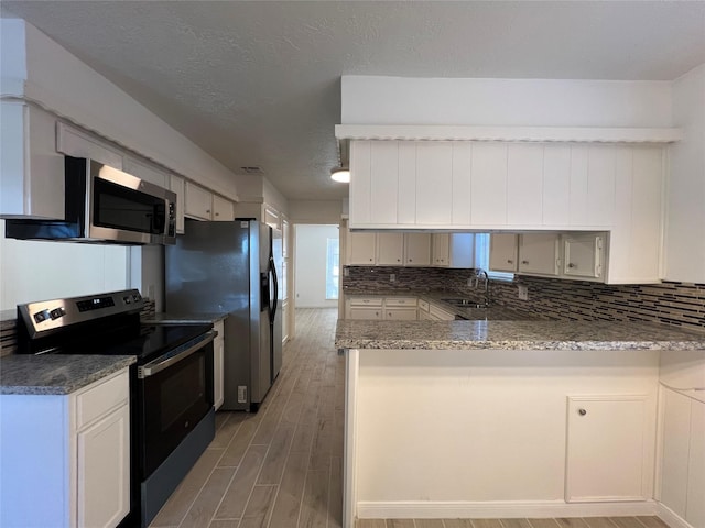 602 Rosewood Dr, Shenandoah, TX 77381 - kitchen with stainless steel appliances, a sink, light wood-style flooring, a peninsula, and backsplash