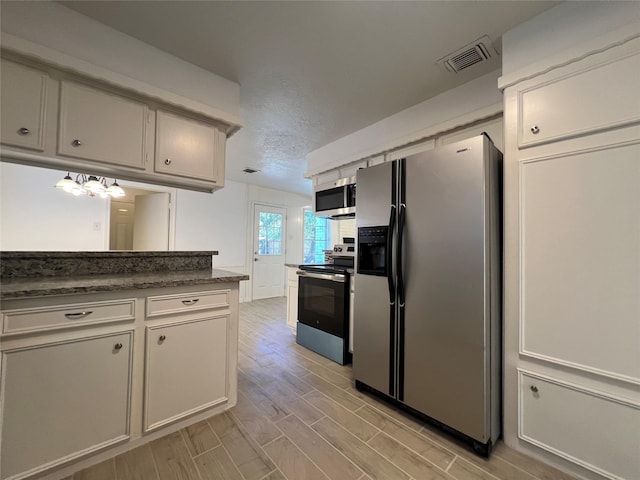 602 Rosewood Dr, Shenandoah, TX 77381 - kitchen with stainless steel appliances, a textured ceiling, light wood-type flooring, and dark stone counters