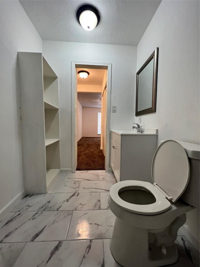 602 Rosewood Dr, Shenandoah, TX 77381 - bathroom featuring baseboards, marble look tile flooring, a textured ceiling, vanity, and toilet
