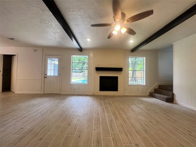 602 Rosewood Dr, Shenandoah, TX 77381 - unfurnished living room featuring beam ceiling, a textured ceiling, light wood-type flooring, healthy amount of natural light, and ceiling fan