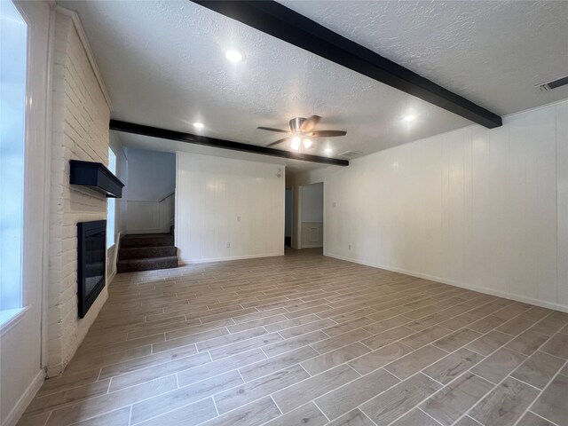 602 Rosewood Dr, Shenandoah, TX 77381 - unfurnished living room featuring beamed ceiling, a textured ceiling, a ceiling fan, stairway, and a fireplace