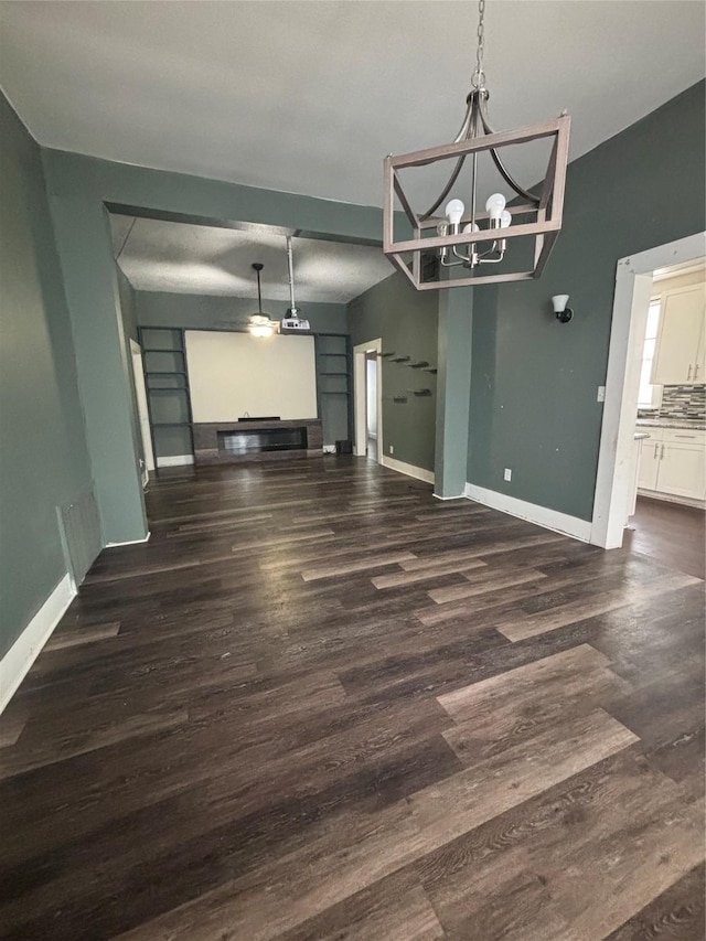 unfurnished dining area featuring baseboards, a chandelier, and wood finished floors