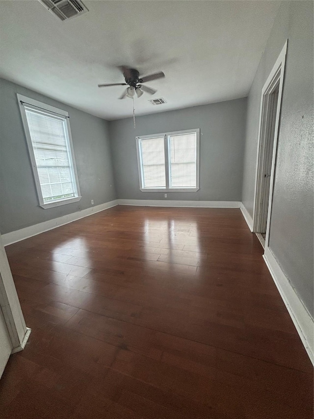 spare room featuring dark wood-style flooring, healthy amount of natural light, and ceiling fan