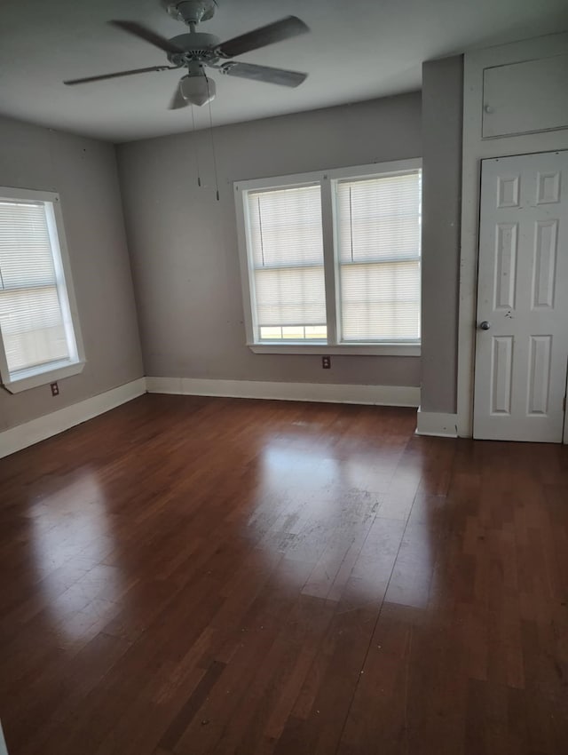 spare room featuring dark wood finished floors, baseboards, and a ceiling fan