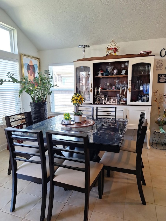 3210 Vintage View Ln, Pearland, TX 77584 - dining space with lofted ceiling, plenty of natural light, light tile patterned floors, and a textured ceiling